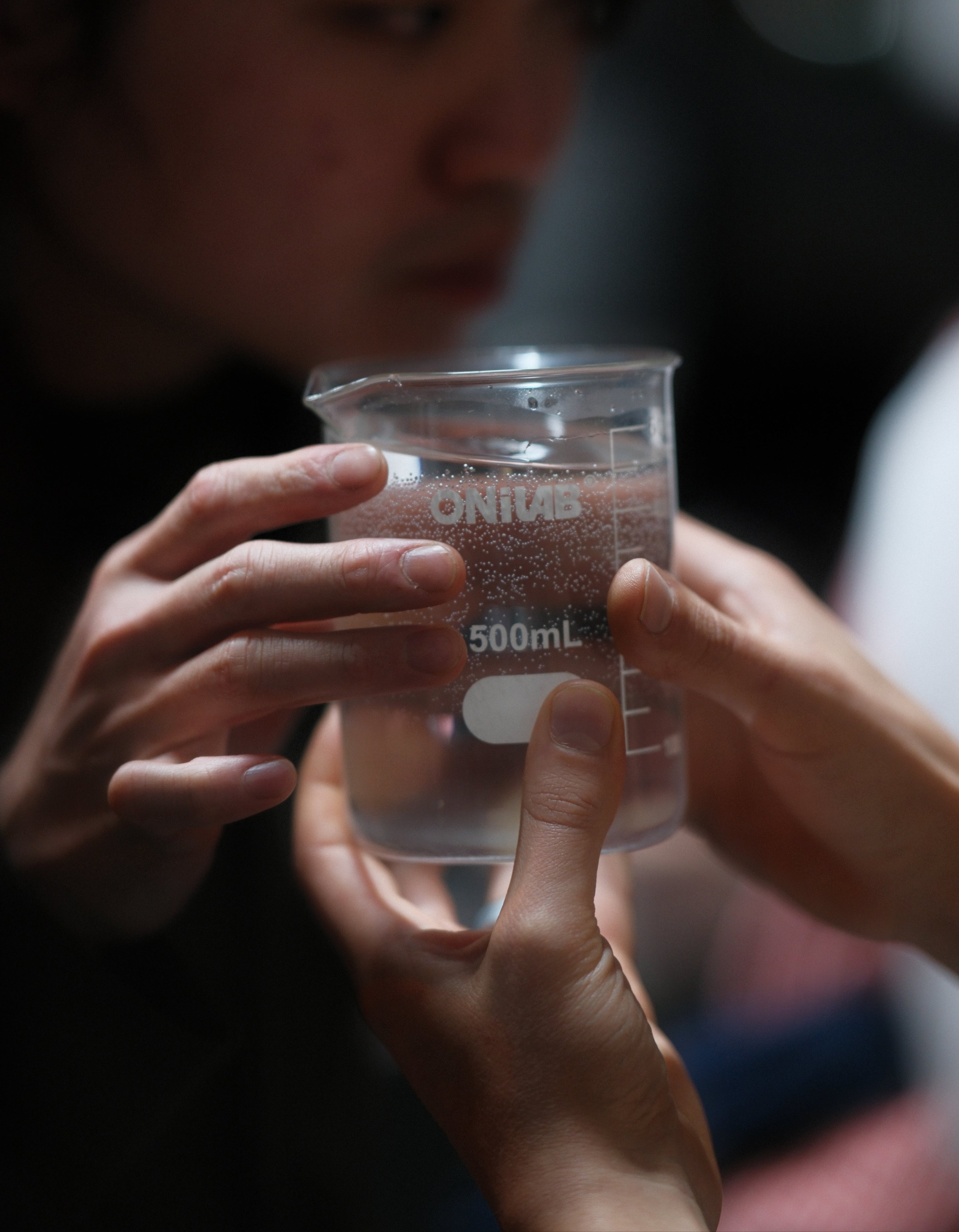 Person holding a water for coffee jar, with a blurred background