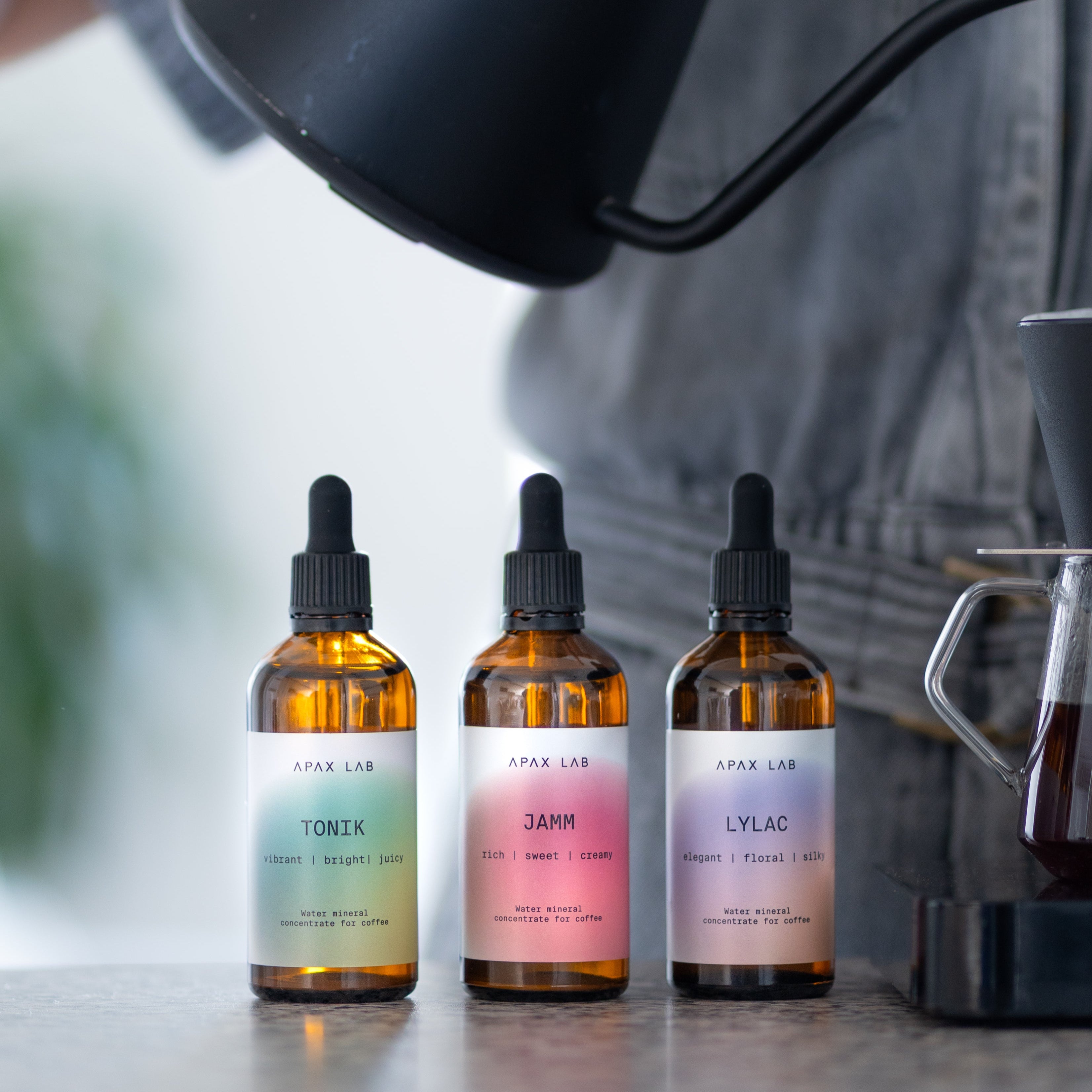 Three Apax Lab bottles on a surface with a blurred background