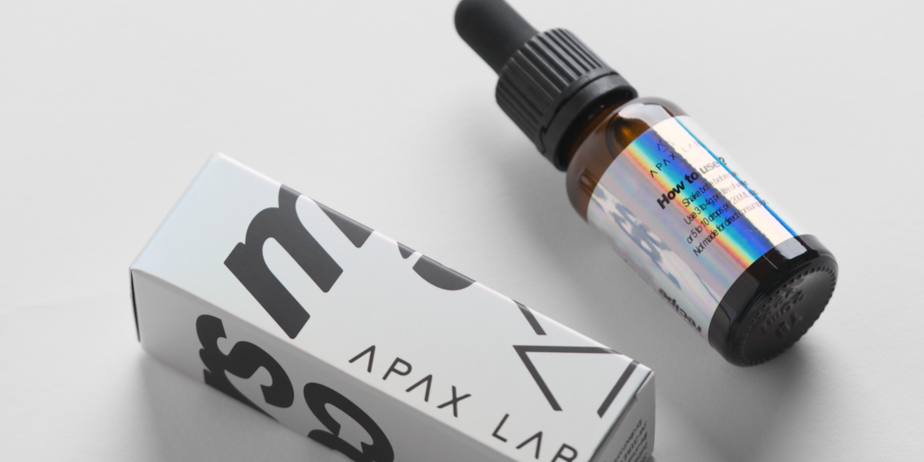 Bottle and box of Motors x Apax Lab on a light gray background