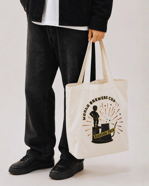 Person holding a tote bag with a logo on a plain background